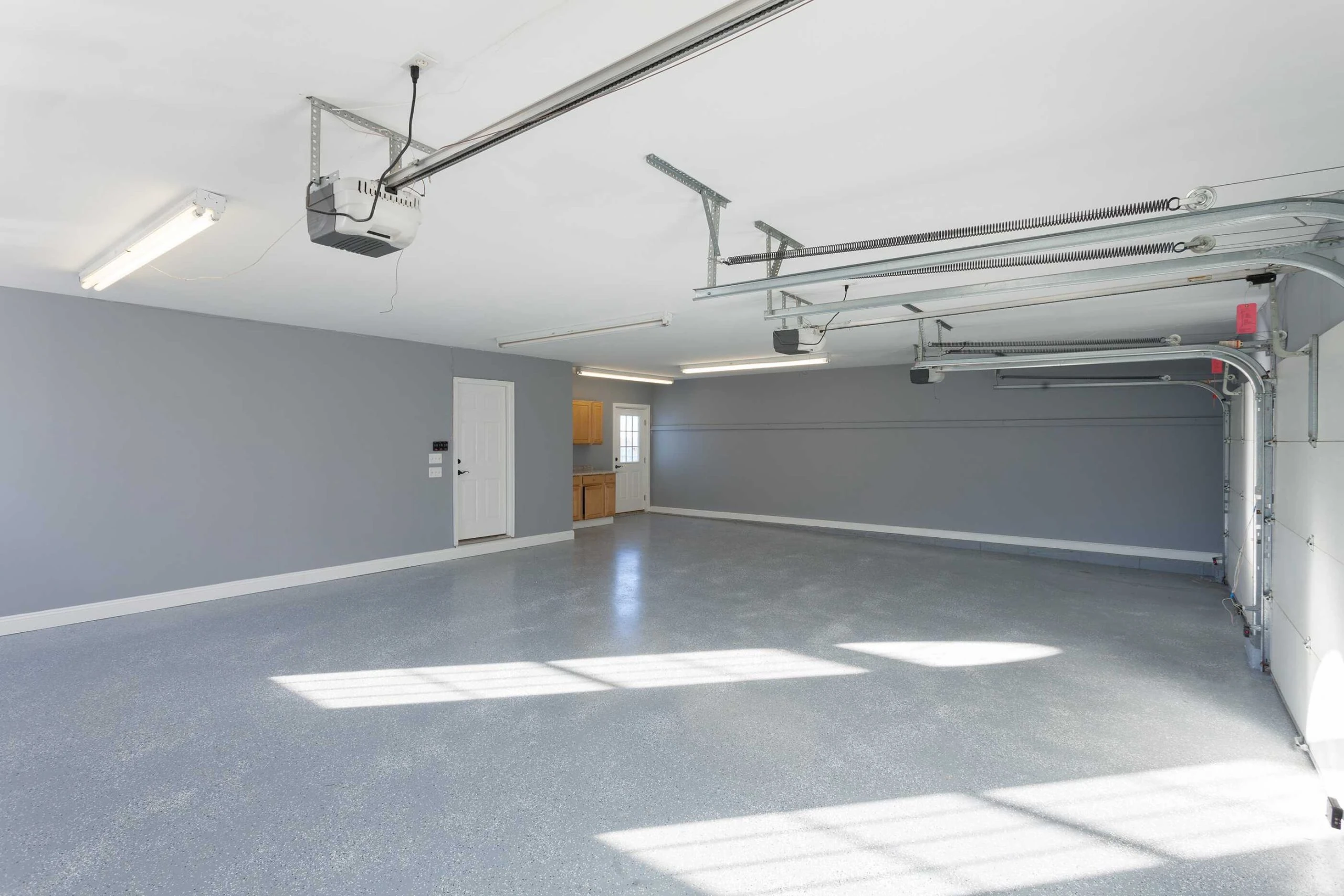 A large empty garage with a white door and a gray wall.